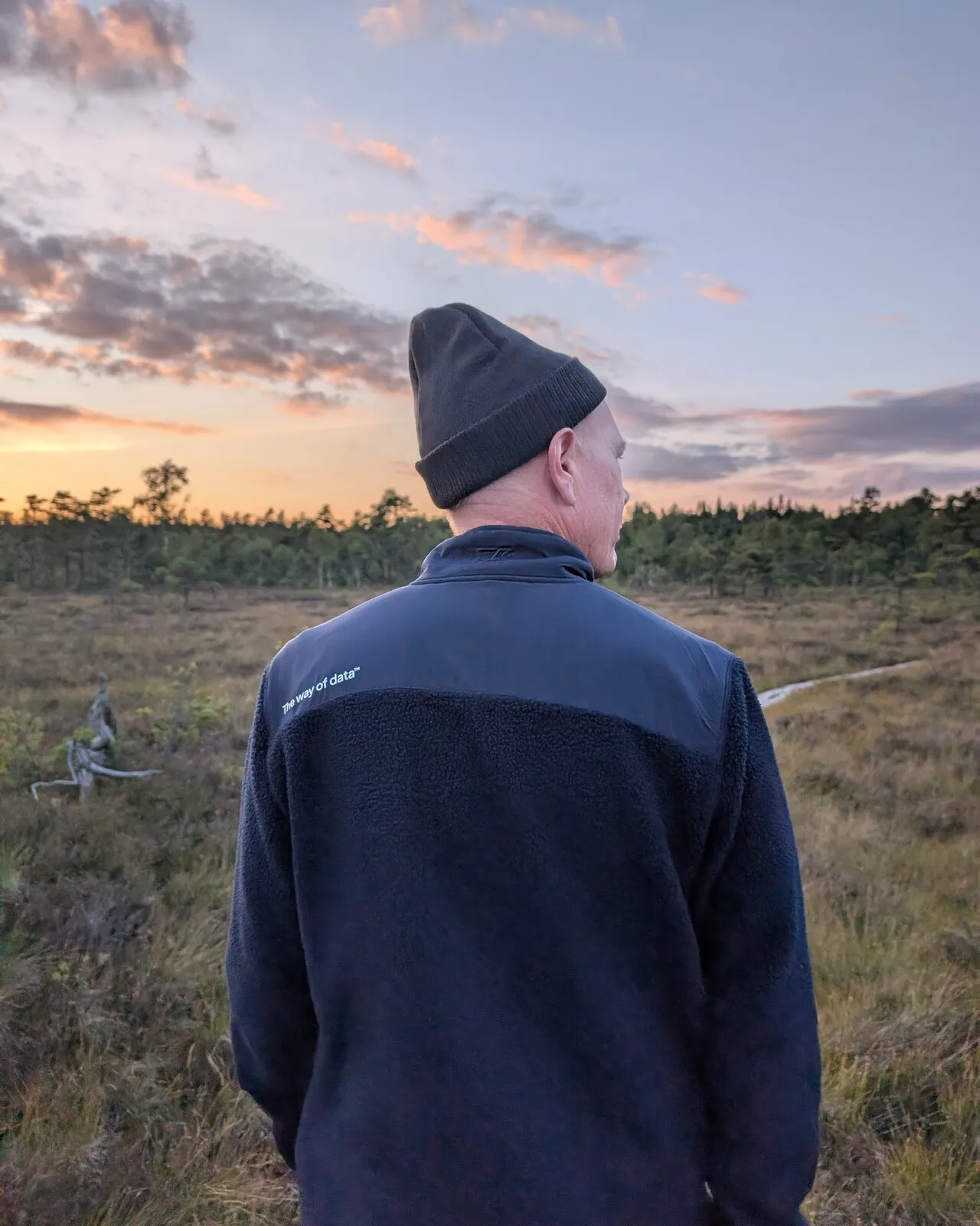 One of the team in a ‘The way of data’ jacket, looking out over a bog at sunset